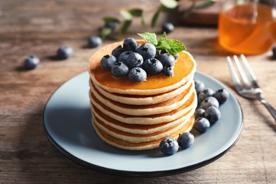 Plate with pancakes and berries on wooden table