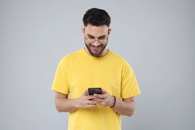 Photo of Happy young man using smartphone on grey background