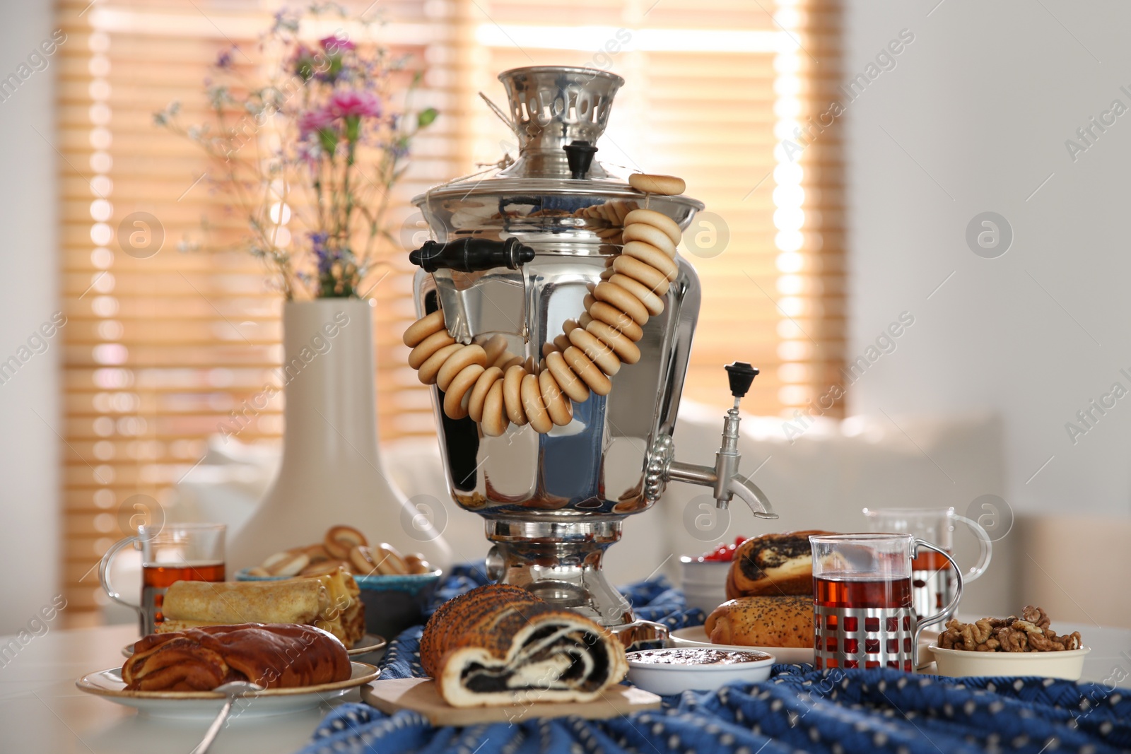 Photo of Traditional Russian samovar with treats on white table at home