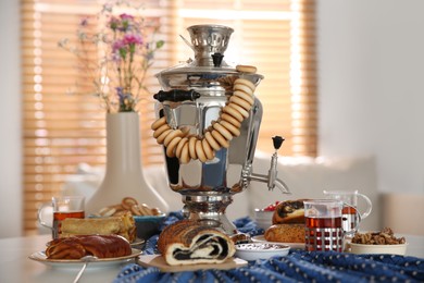 Photo of Traditional Russian samovar with treats on white table at home