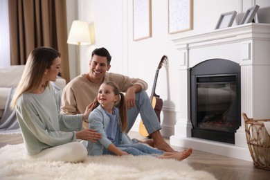 Photo of Happy family resting near fireplace at home