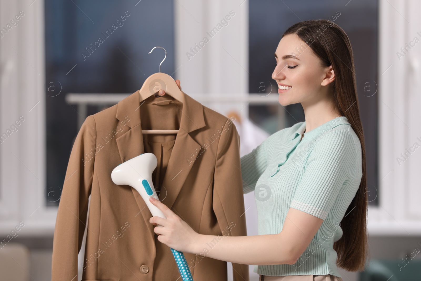 Photo of Woman steaming jacket on hanger at home