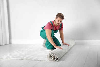 Photo of Man rolling out new carpet flooring indoors