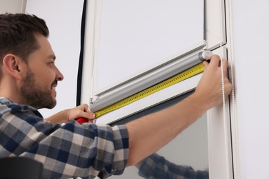 Man measuring window with tape indoors. Roller blinds installation