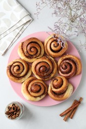 Many tasty cinnamon rolls on white table, flat lay