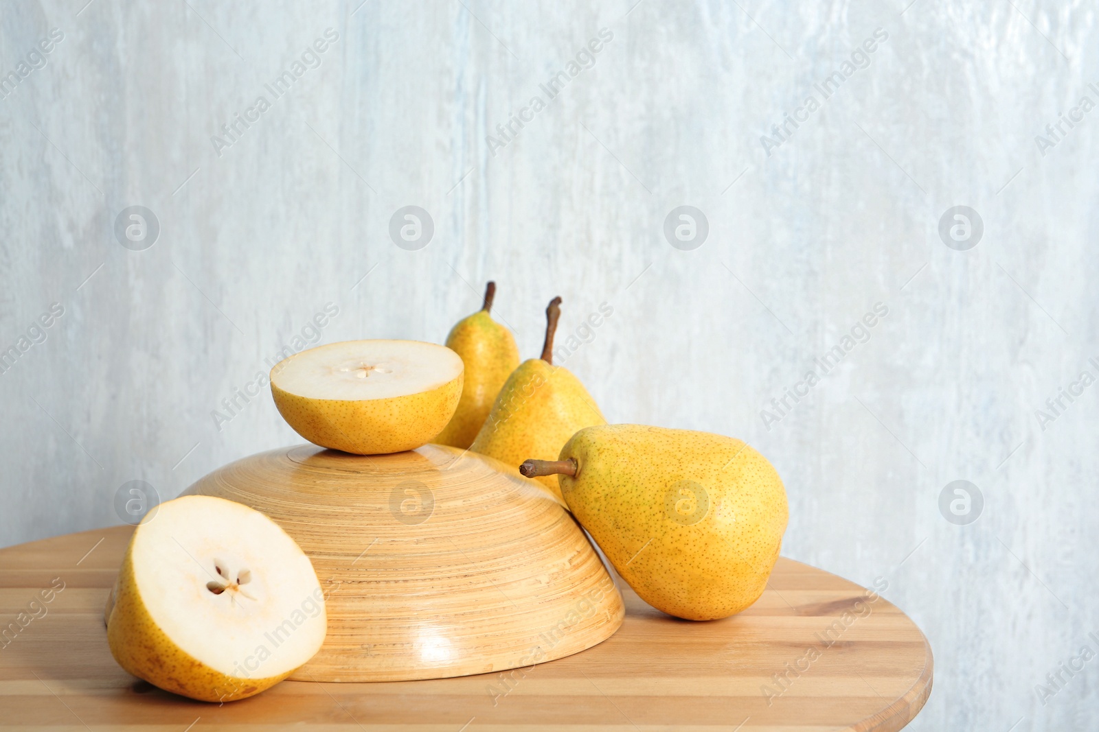 Photo of Fresh ripe pears on wooden table against light background