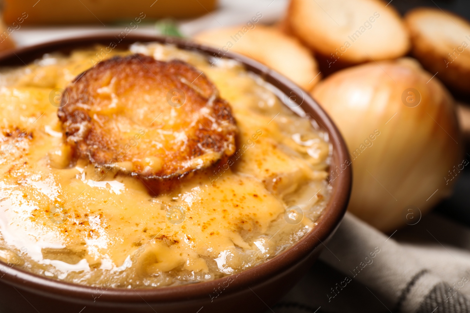 Photo of Tasty homemade french onion soup served in ceramic bowl, closeup