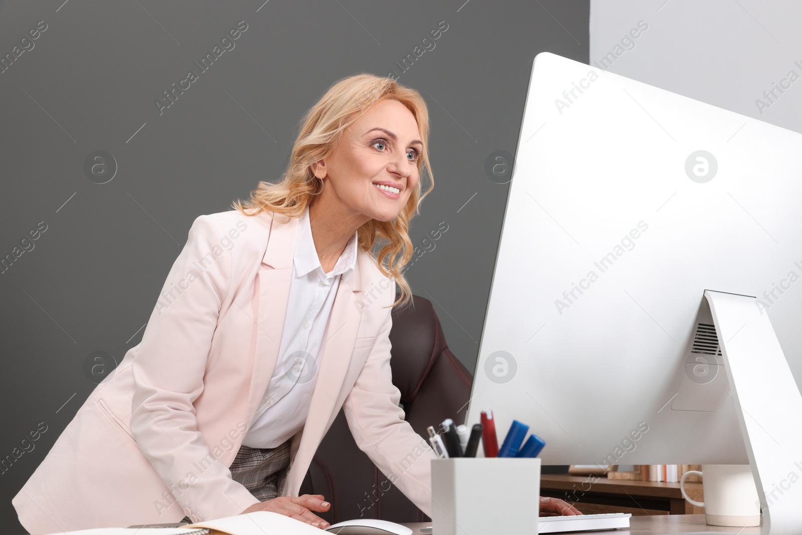 Photo of Happy lady boss working on computer in office. Successful businesswoman