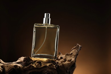 Photo of Luxury men`s perfume in bottle against brown background, space for text