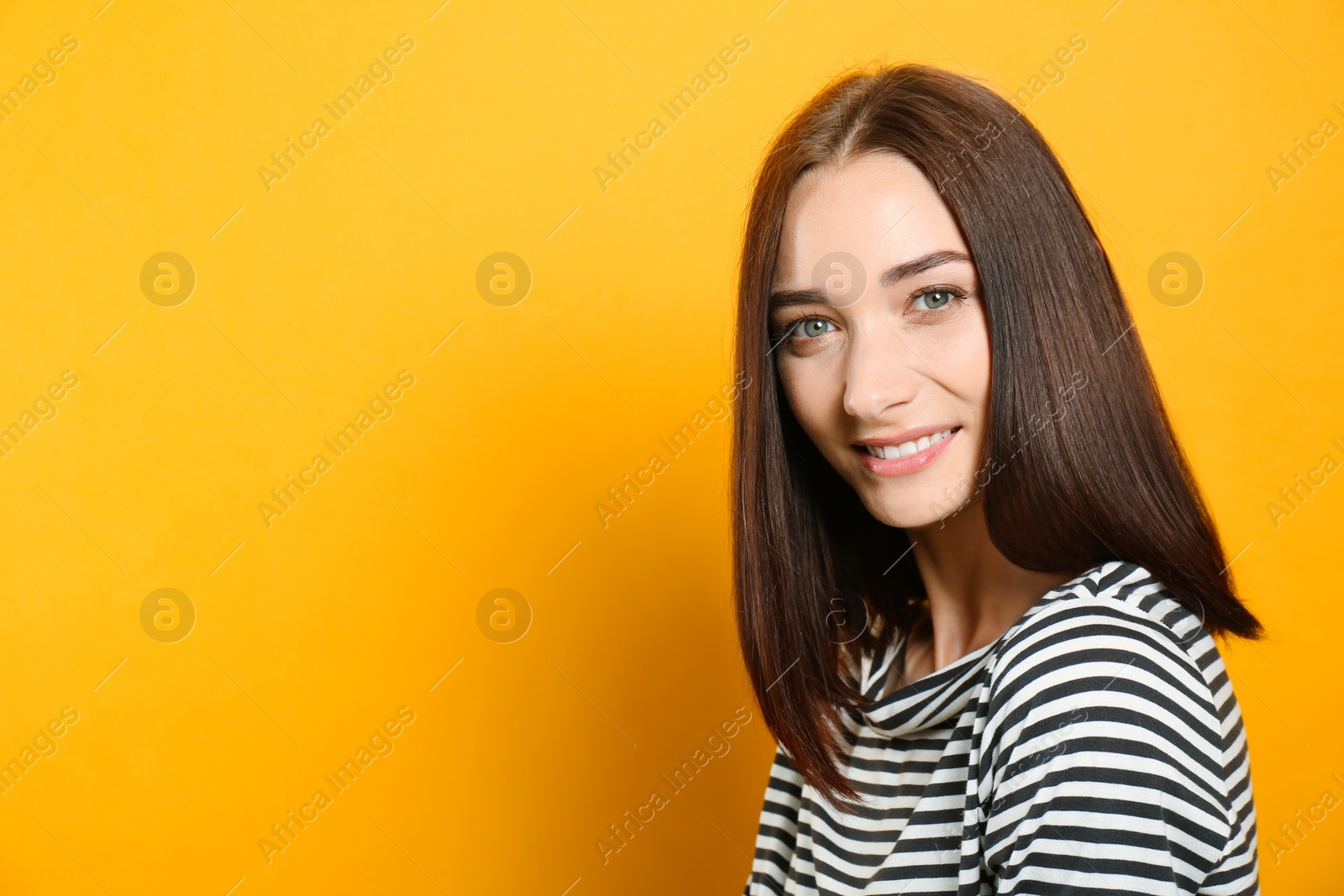 Photo of Portrait of pretty young woman with gorgeous chestnut hair and charming smile on yellow background, space for text