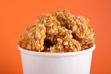 Photo of Bucket with yummy nuggets on orange background, closeup