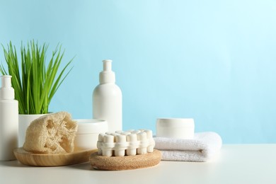 Photo of Different bath accessories and houseplant on white table against light blue background. Space for text