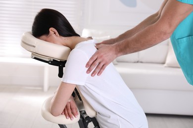 Photo of Woman receiving massage in modern chair indoors