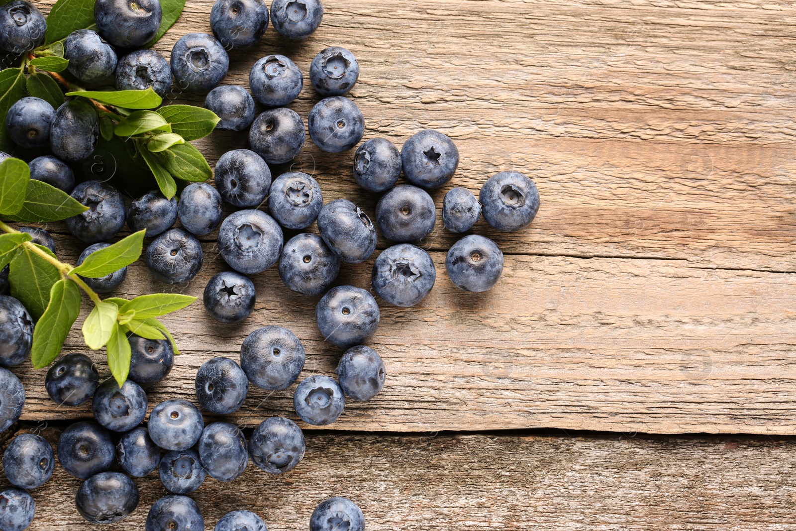 Photo of Tasty fresh blueberries on wooden table, flat lay. Space for text