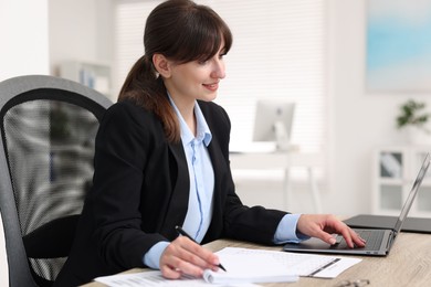 Smiling secretary working at table in office