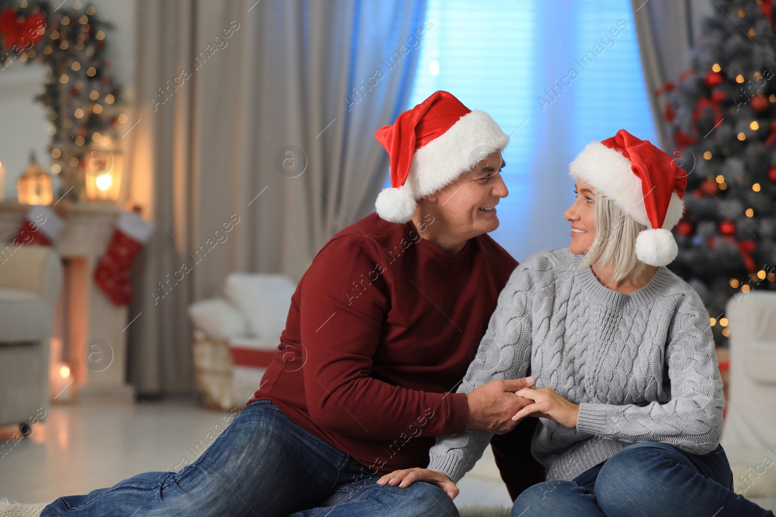 Photo of Happy mature couple in Santa hats at home. Christmas celebration