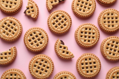 Tasty sandwich cookies with cream on pink background, flat lay