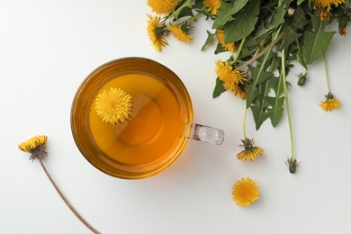 Photo of Delicious fresh tea and beautiful dandelion flowers on white background, top view