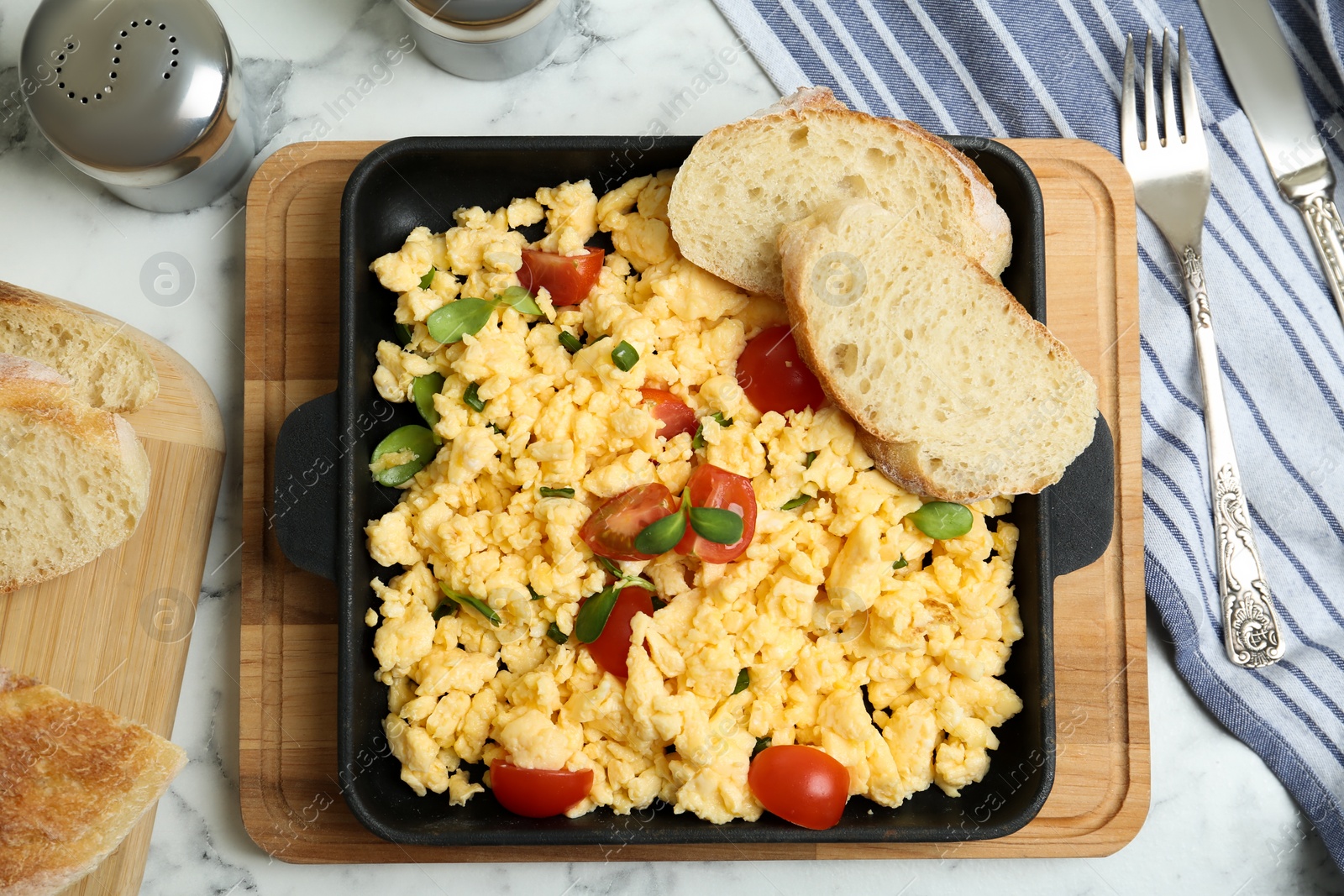 Photo of Tasty scrambled eggs served on white marble table, flat lay