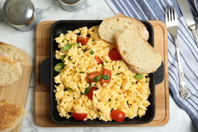 Tasty scrambled eggs served on white marble table, flat lay