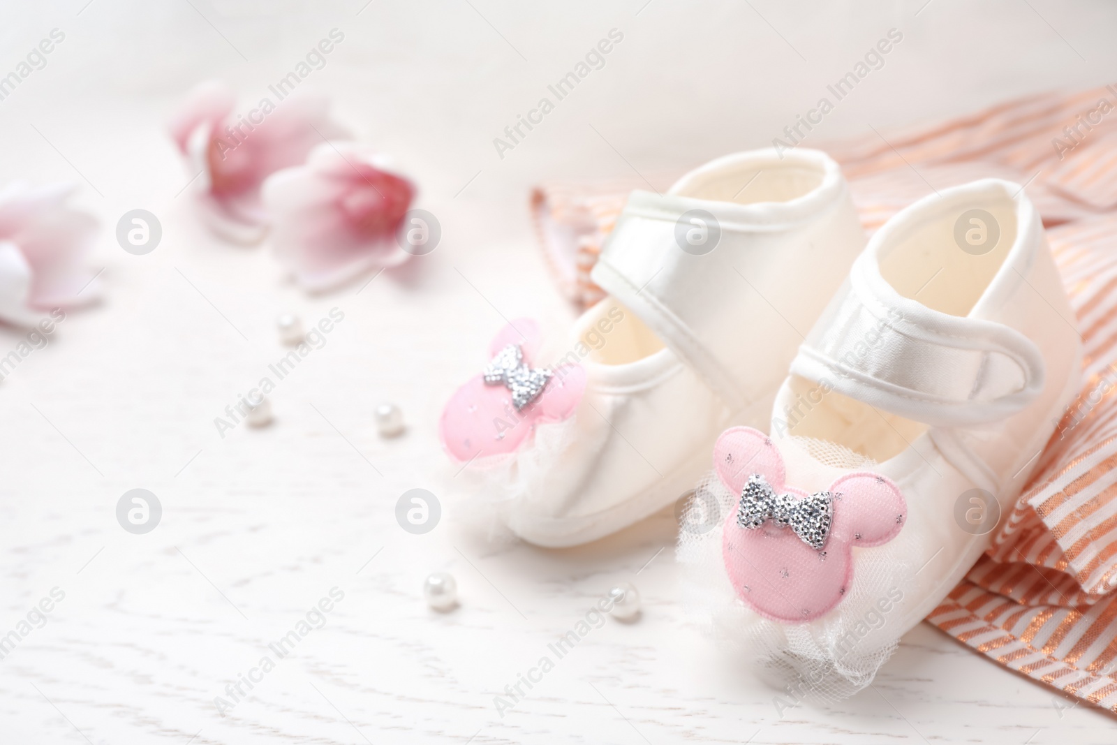 Photo of Pair of cute baby sandals and clothes on table