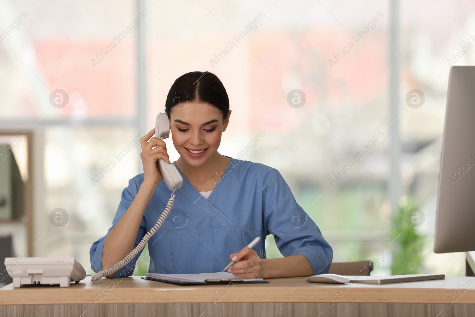 Photo of Receptionist talking on phone at countertop in hospital