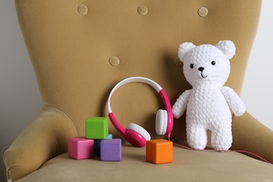 Baby songs. Toy bear, headphones and cubes on armchair