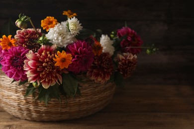 Photo of Beautiful wild flowers and leaves in wicker basket on wooden table