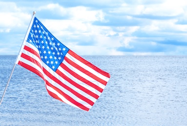 Woman with American flag near river on cloudy day. Space for text