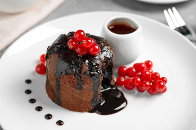 Photo of Delicious warm chocolate lava cake with berries on plate, closeup