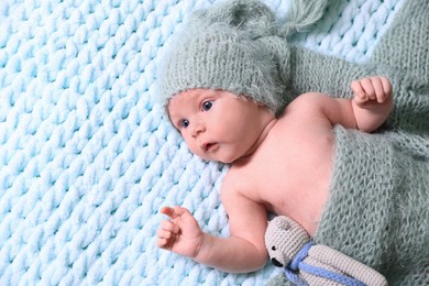 Cute newborn baby with pacifier and crochet toy on light blue blanket, top view. Space for text