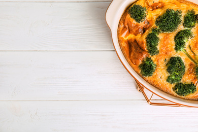Photo of Tasty broccoli casserole in baking dish on white wooden table, top view. Space for text