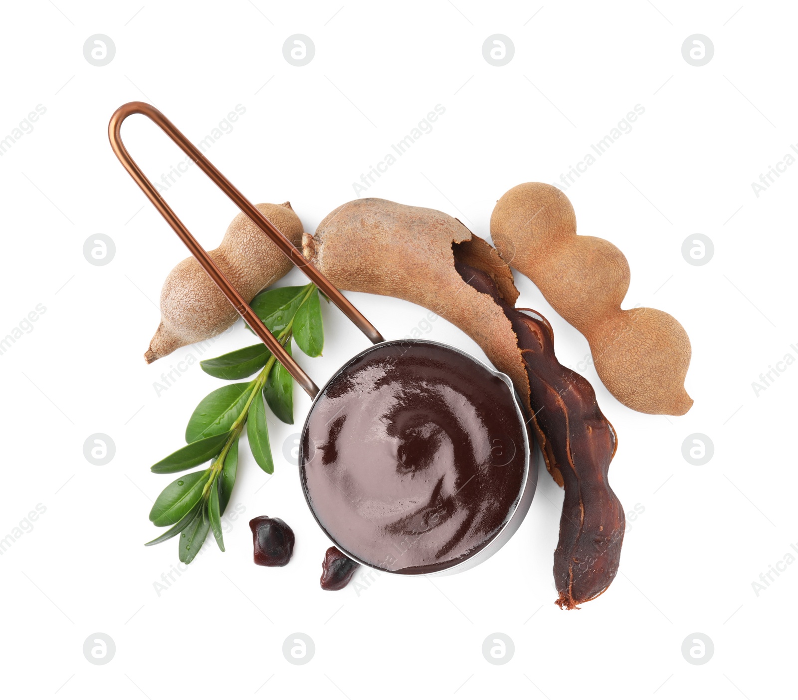 Measuring cup with tasty tamarind sauce, leaves and fresh pods isolated on white, top view Photo of Measuring cup with tasty tamarind sauce, leaves and fresh pods isolated on white, top view