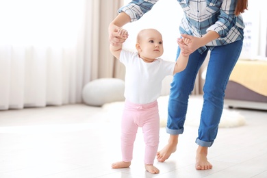 Baby taking first steps with mother's help at home