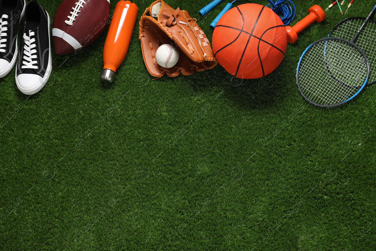 Photo of Different sports equipment on green grass, flat lay. Space for text