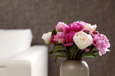 Photo of Vase with bouquet of beautiful peonies in room, space for text