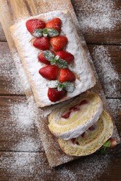 Pieces of delicious cake roll with strawberries and cream on wooden table, top view