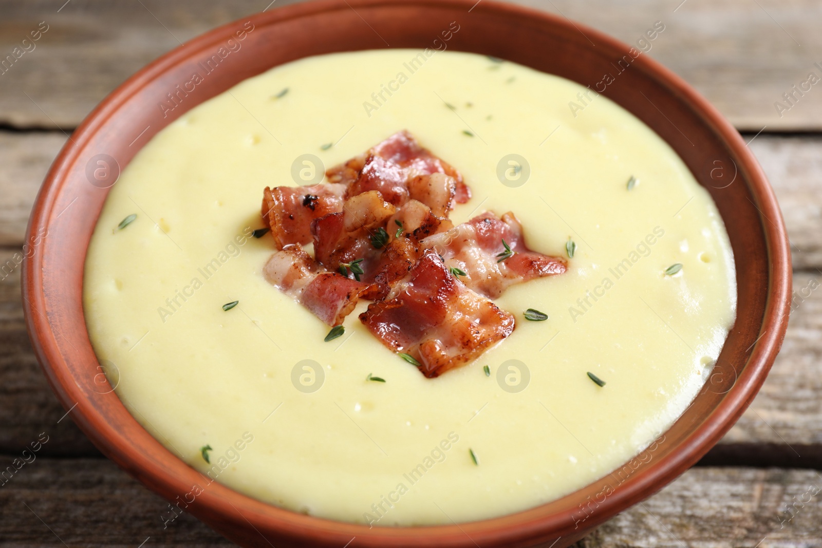 Photo of Tasty potato soup with bacon in bowl on table, closeup