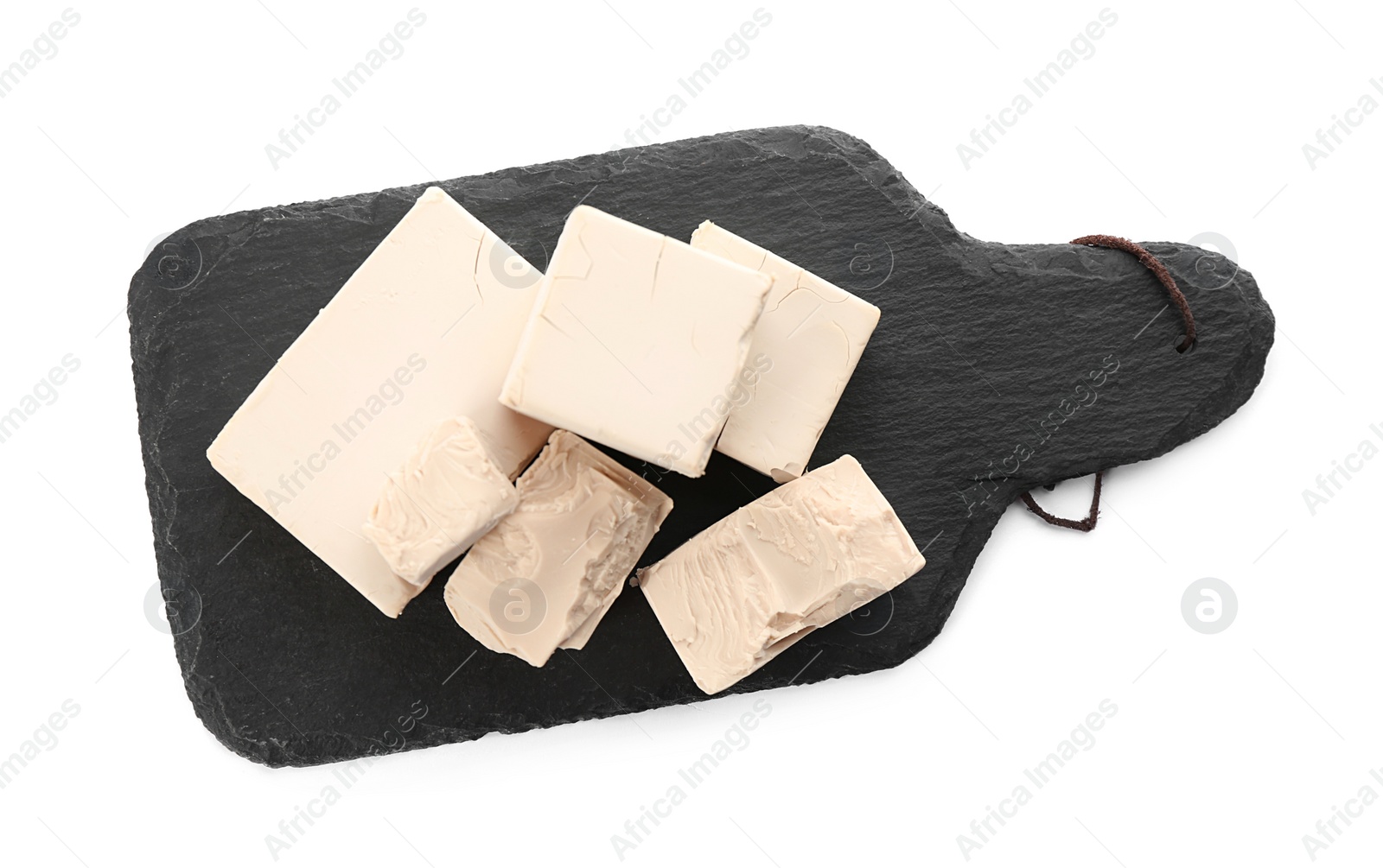 Photo of Slate board with pieces of compressed yeast on white background, top view