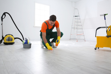 Professional janitor cleaning floor with brush and detergent after renovation