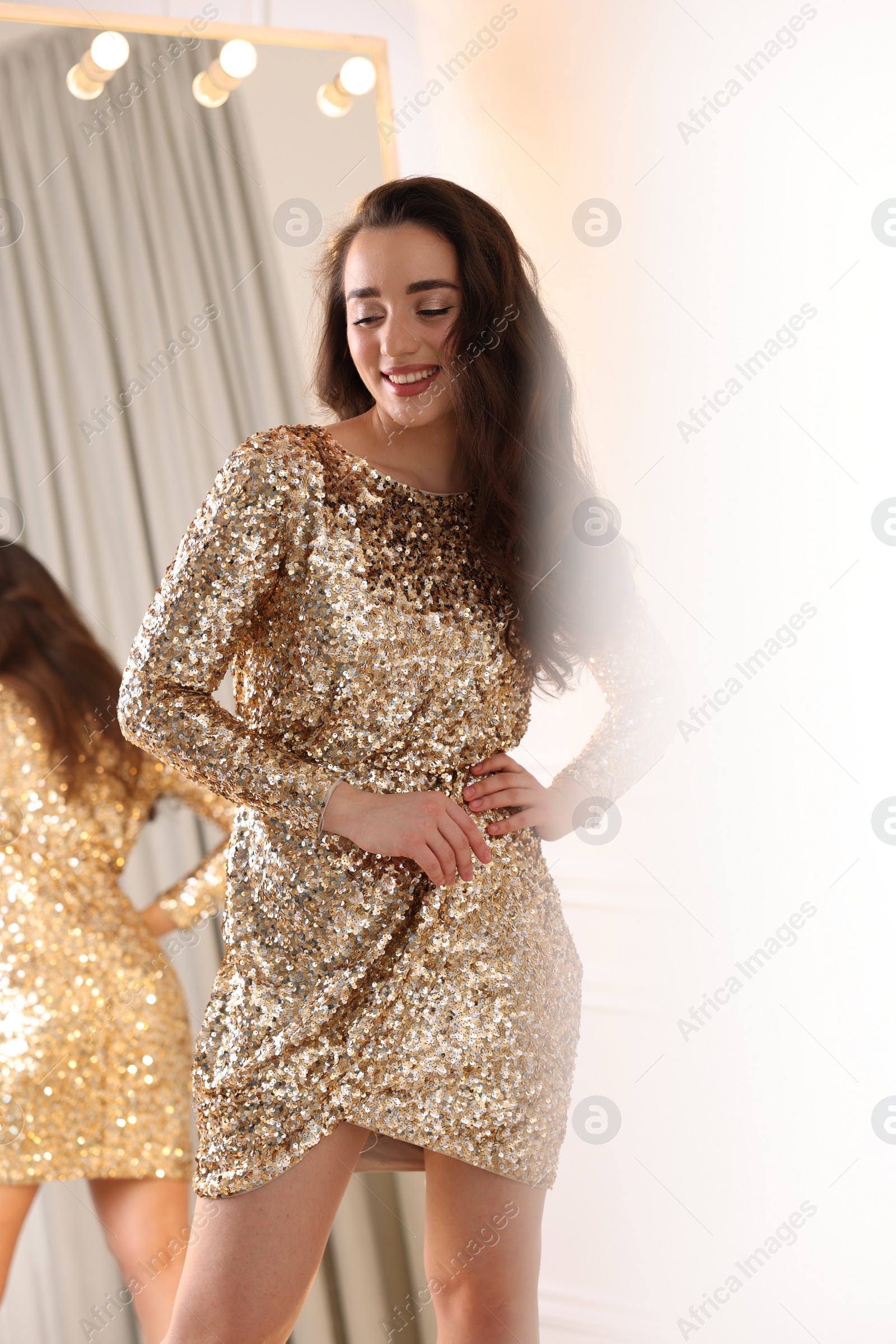 Photo of Beautiful woman in elegant dress near mirror indoors