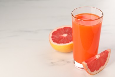 Tasty grapefruit juice in glass and fresh fruit on white table. Space for text