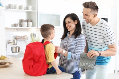 Young parents helping their little child get ready for school at home