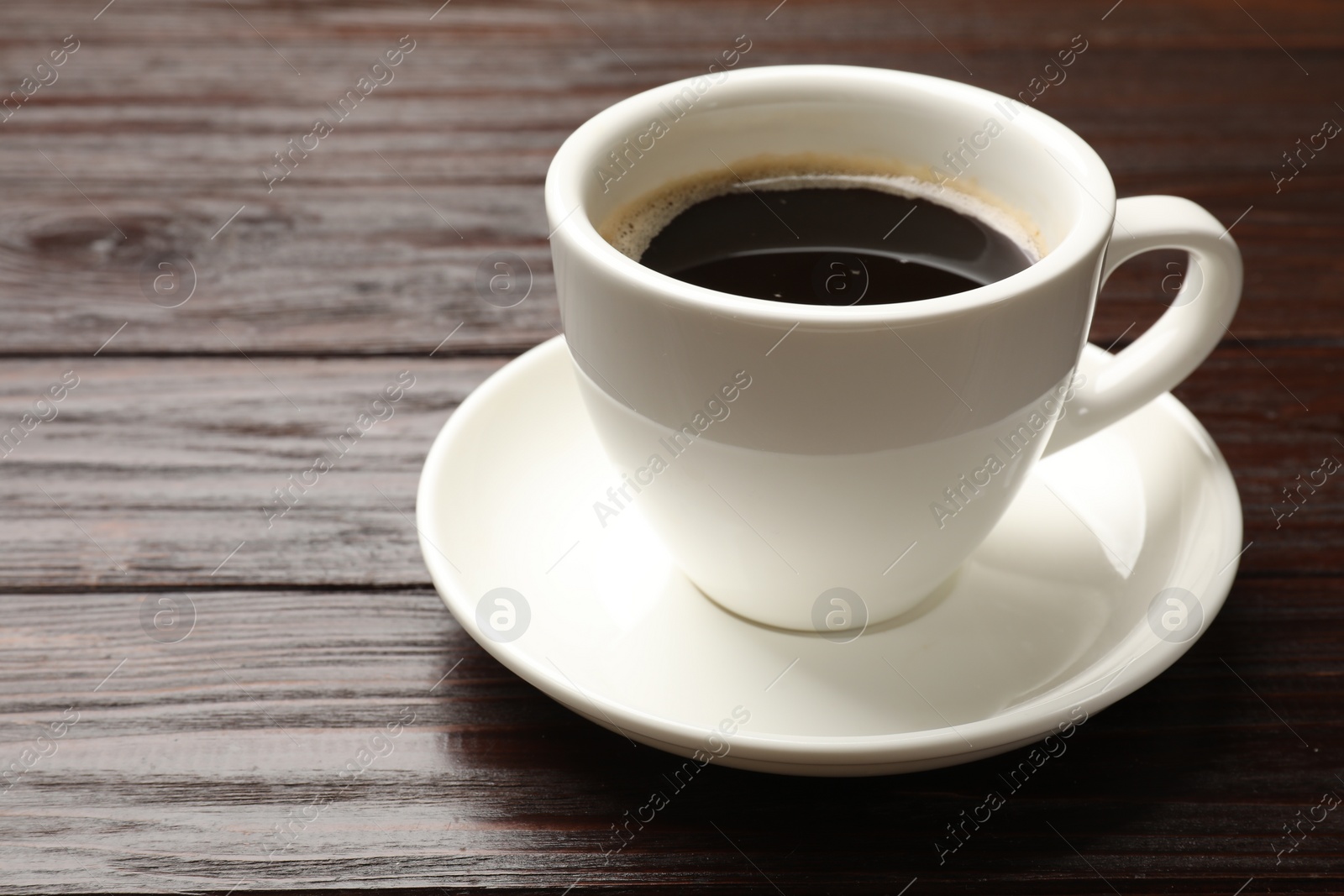 Photo of Cup of aromatic coffee on wooden table, closeup. Space for text