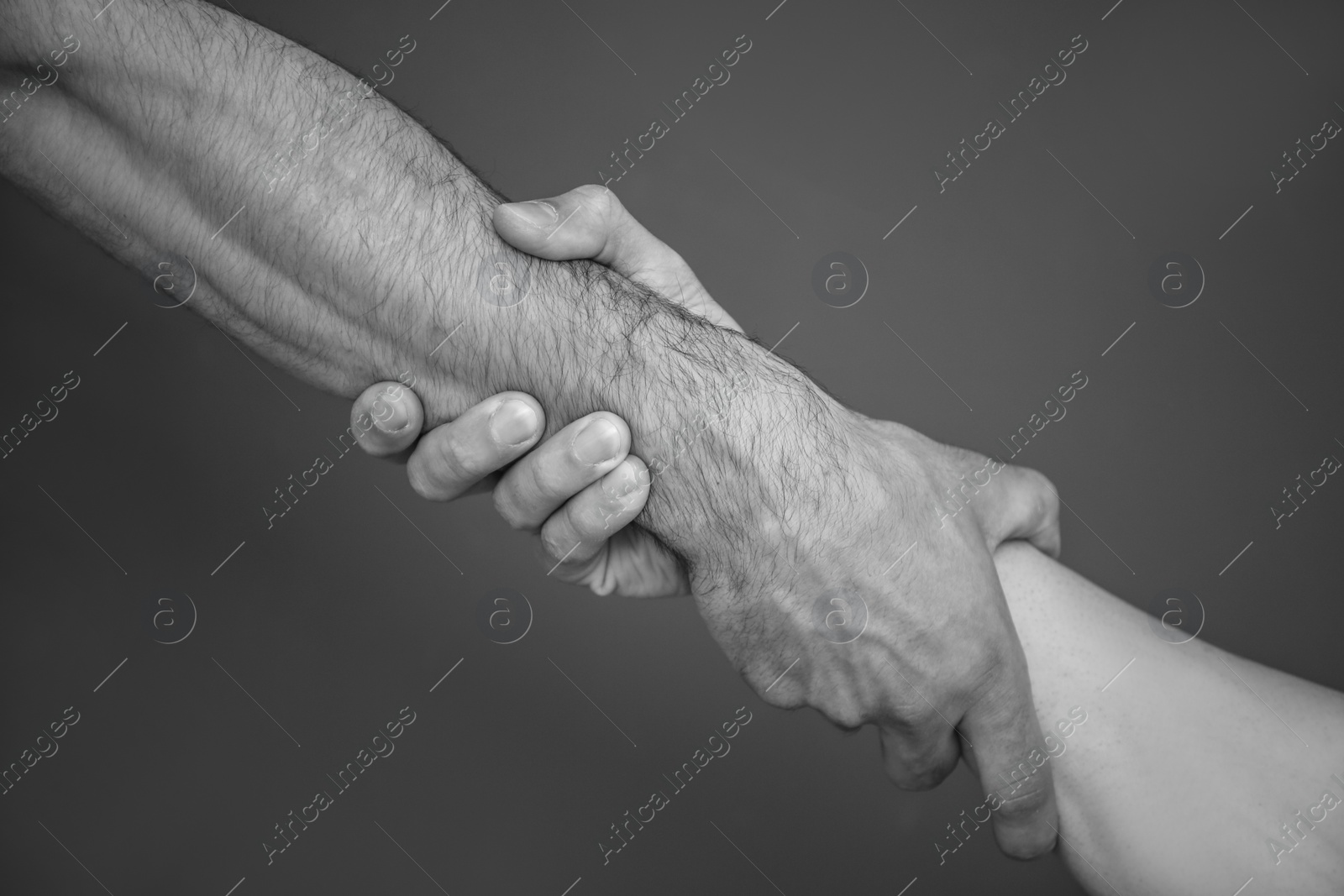 Photo of Men holding hands together on grey background, black and white effect. Unity concept