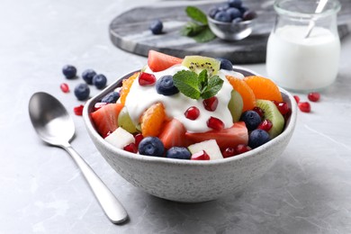 Photo of Delicious fruit salad with yogurt on grey table
