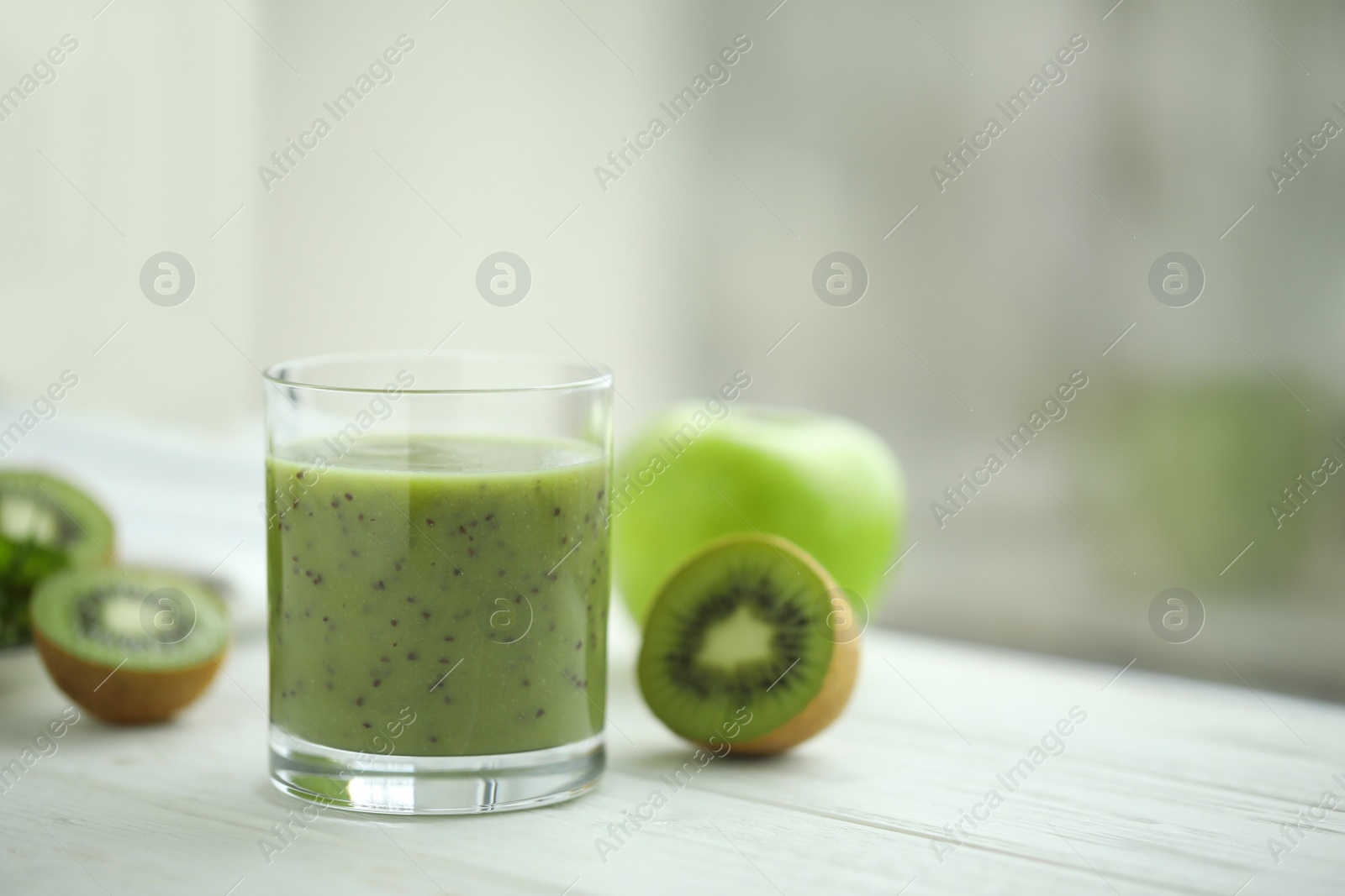 Photo of Delicious kiwi smoothie and fresh fruits on white wooden table. Space for text