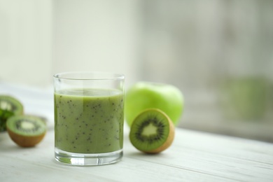 Photo of Delicious kiwi smoothie and fresh fruits on white wooden table. Space for text