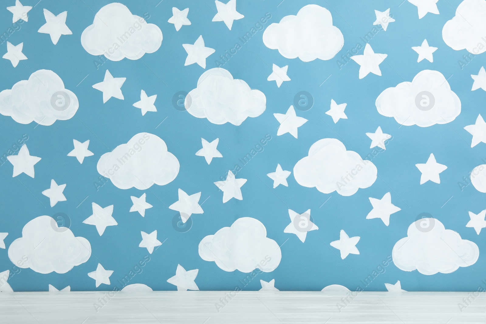 Photo of White wooden table near wall with painted blue sky. Idea for baby room interior