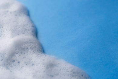 Photo of White foam on light blue background. Space for text